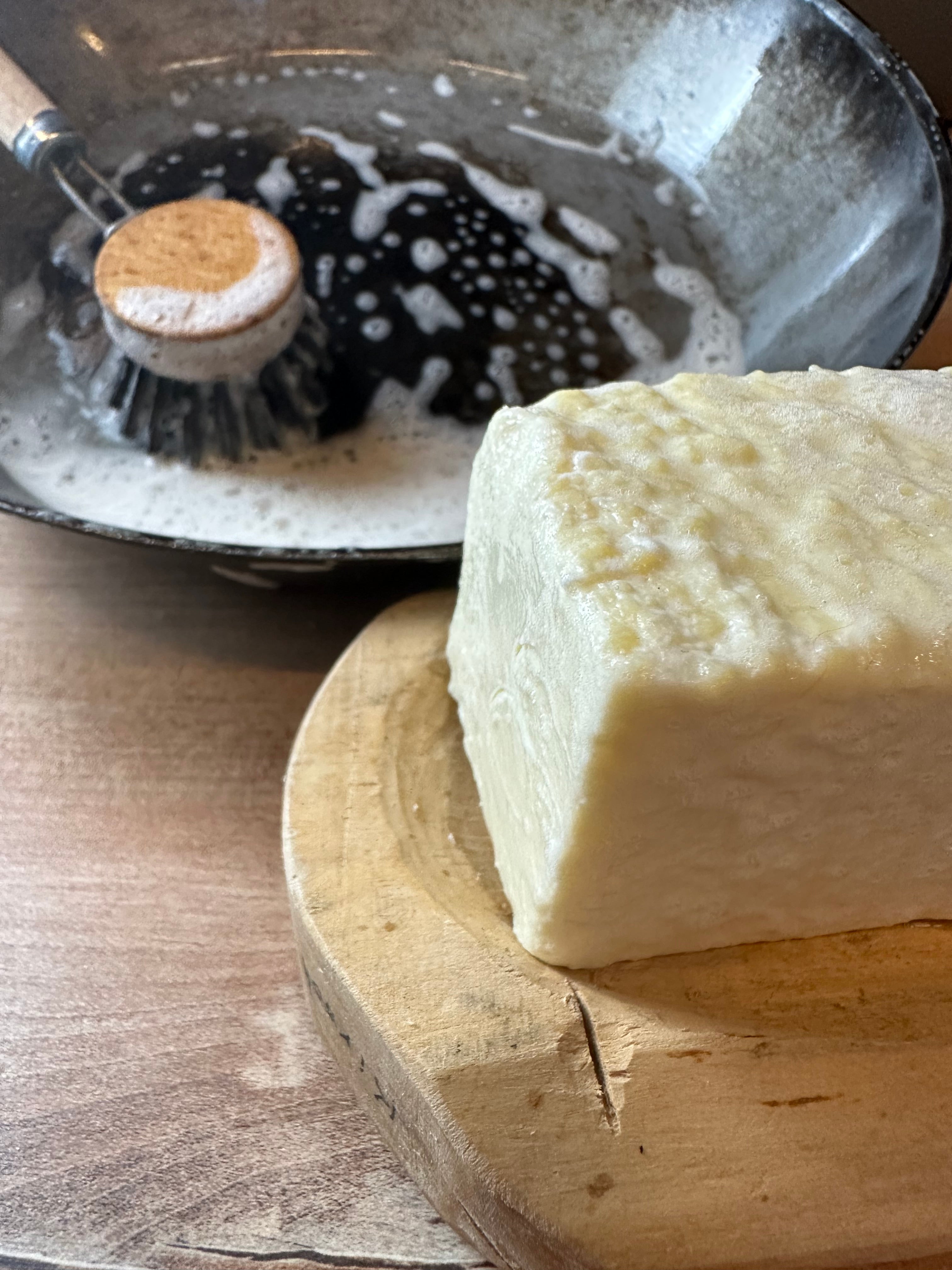 Mit der Kernseife wird eine Pfanne geputzt. Sie schäumt.