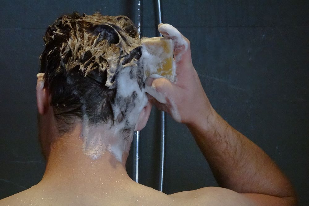 Die Haar Kraft Seife in Anwendung. Haare werden mit der Haar Kraft gewaschen. Der Kopf ist mit Schaum bedeckt.